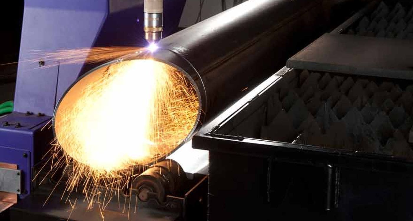 Cutting head profiling a large-diameter steel pipe, sparks streaming from the kerf